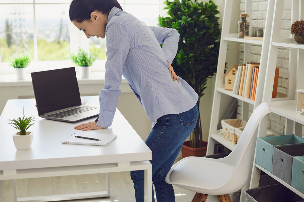 Woman sitting up from desk with sciatica pain.